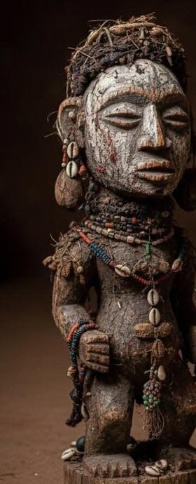 A carved wooden figure decorated with beads and cowrie shells