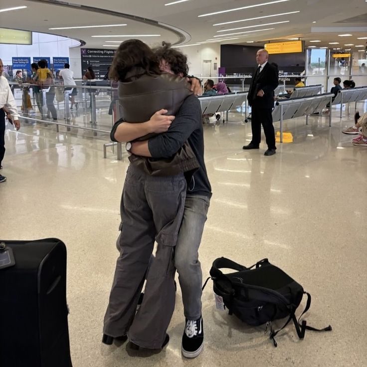 Two people holding each other in an airport arrivals hall