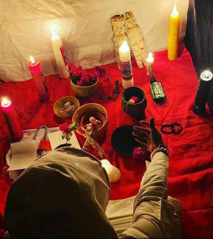 Candles, flowers and small bowls set out on red cloth for a ritual