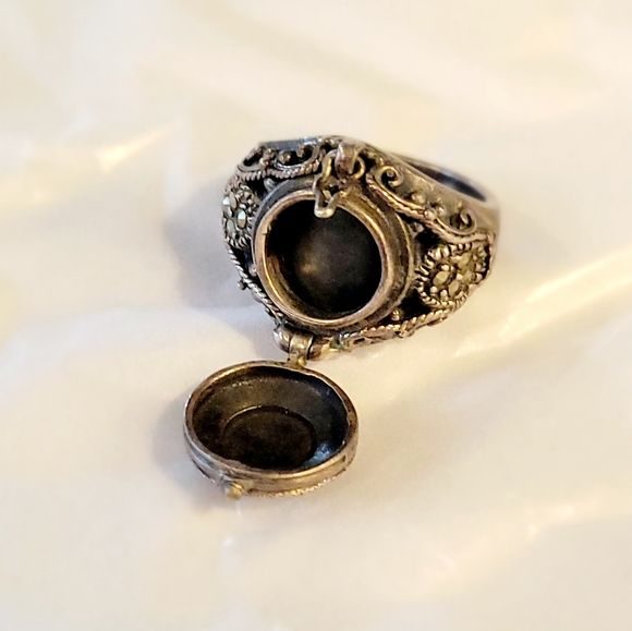 A silver locket ring, open to show the space inside